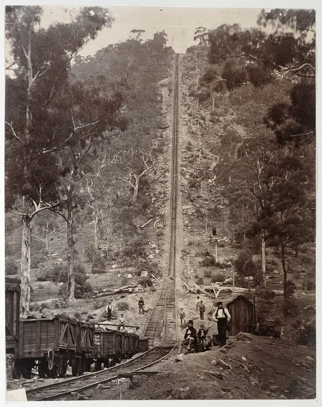 A steep rail incline, wagons and people at Joadja, photographed around 1885.