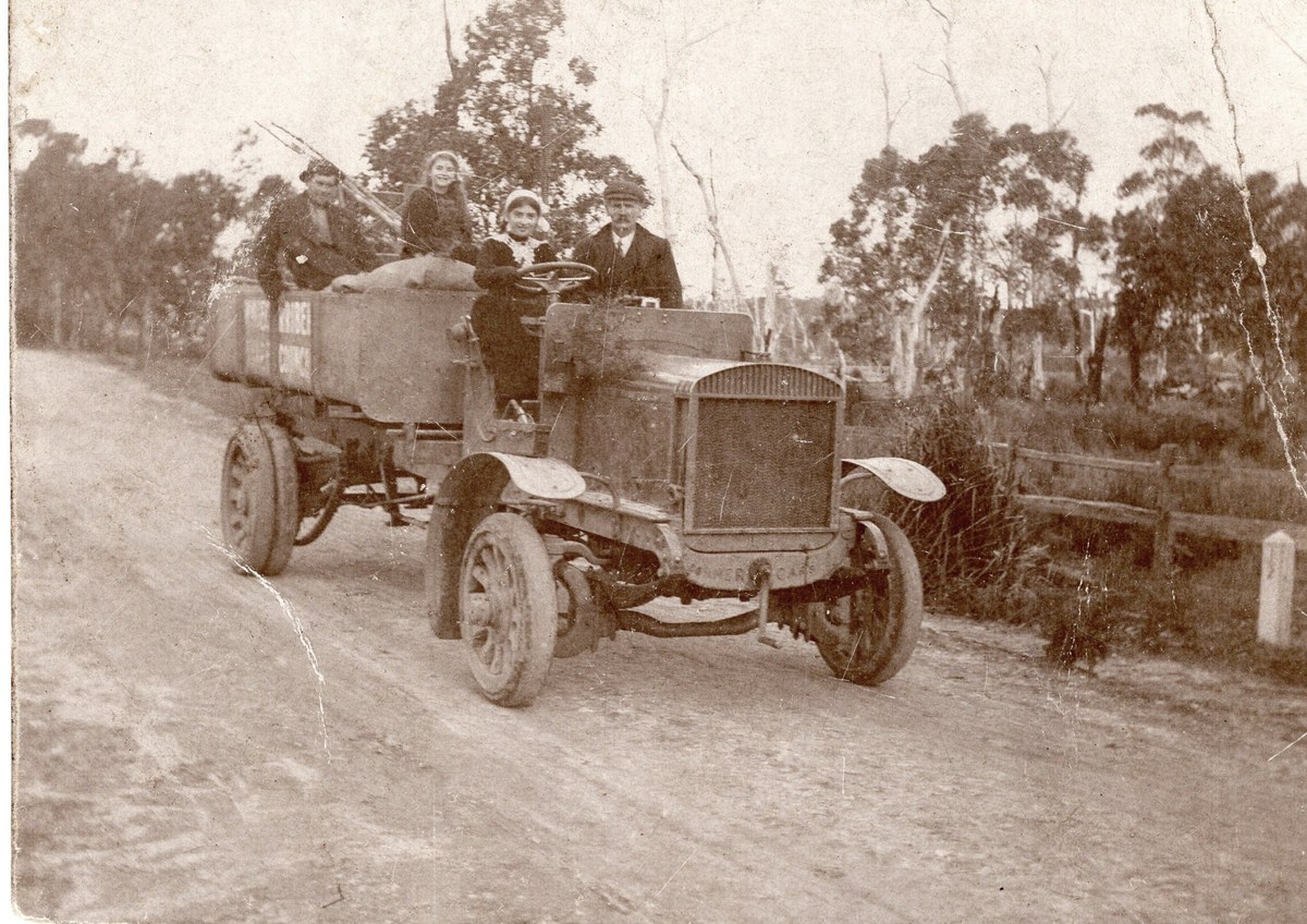 Driver and passengers in an early truck on a country road, captioned Wingecarribee Shire Council truck circa 1917.